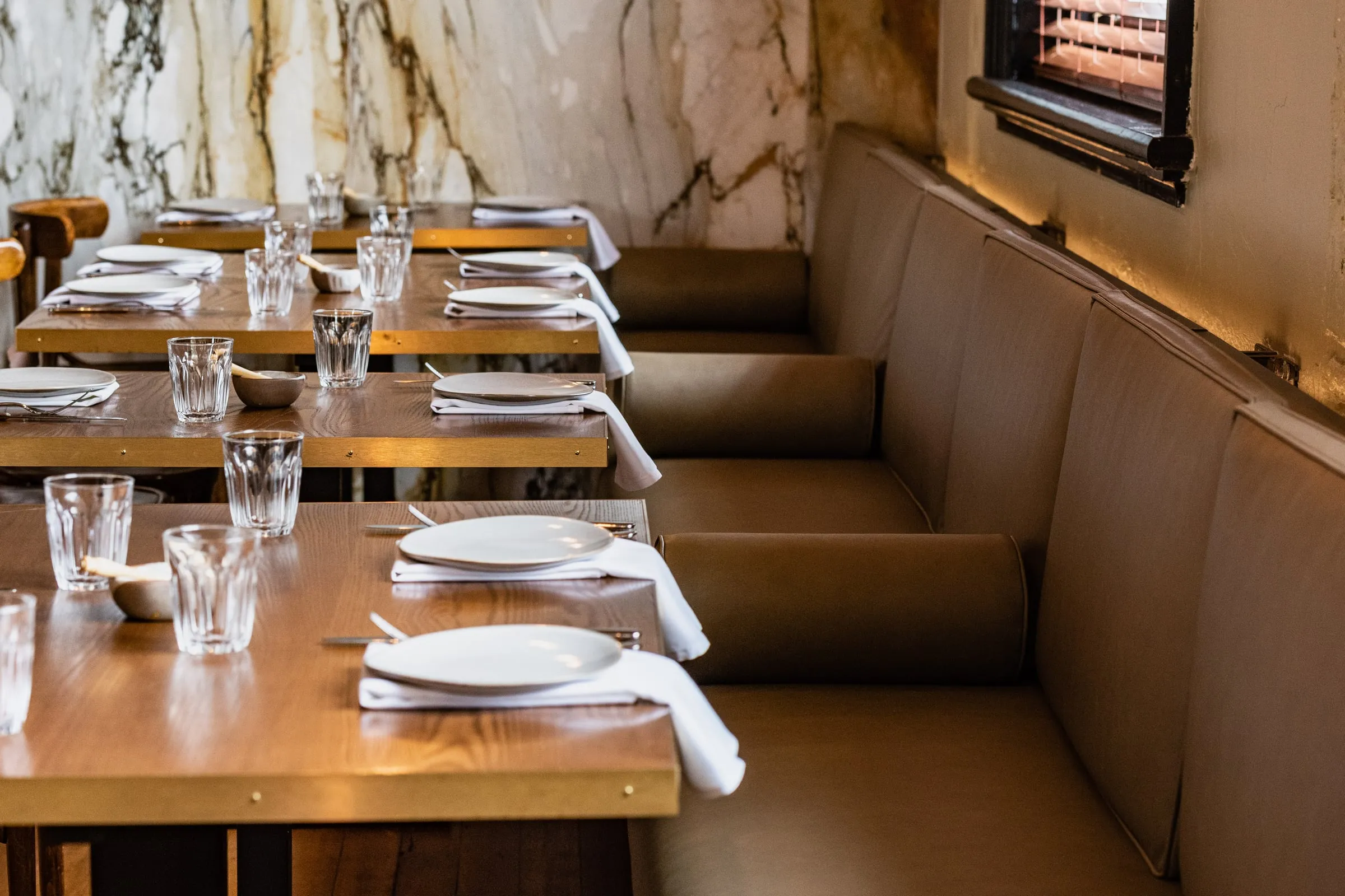 Olive leather banquette run beside a book-matched Marble wall