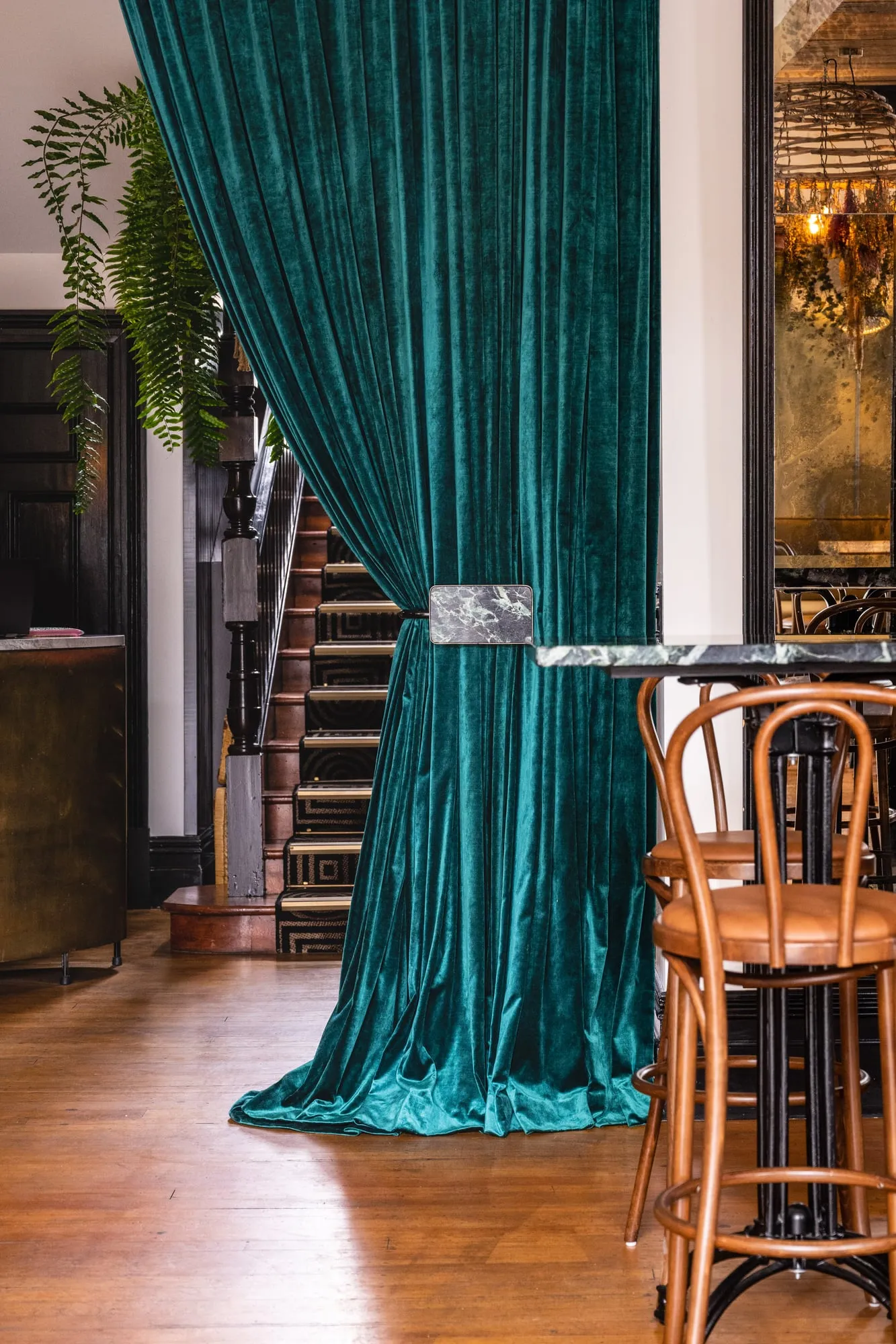 Bottle-green velvet curtain with a Marble tieback beside a heritage stair