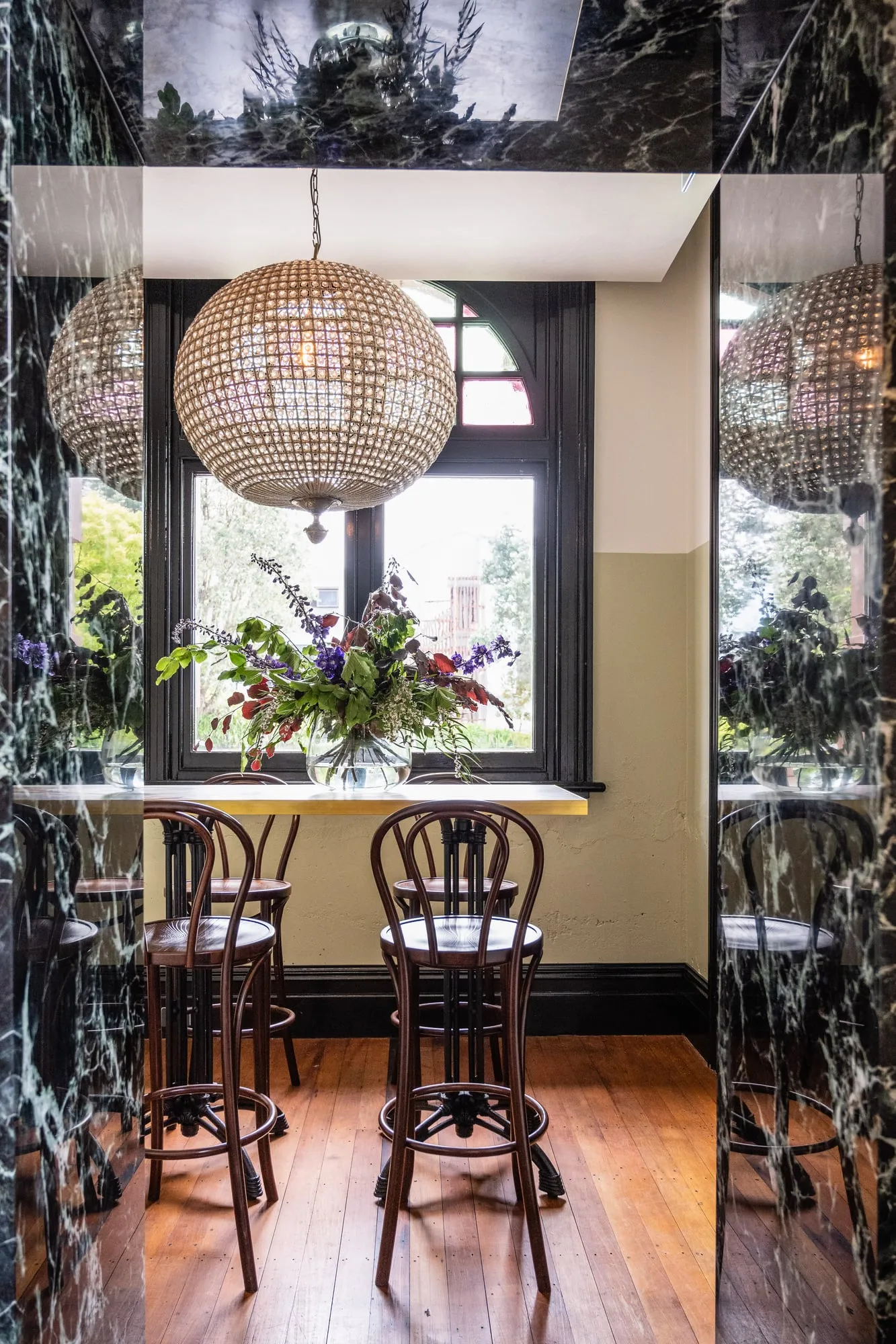Window nook framed by a Verde Antico Marble portal under a globe chandelier