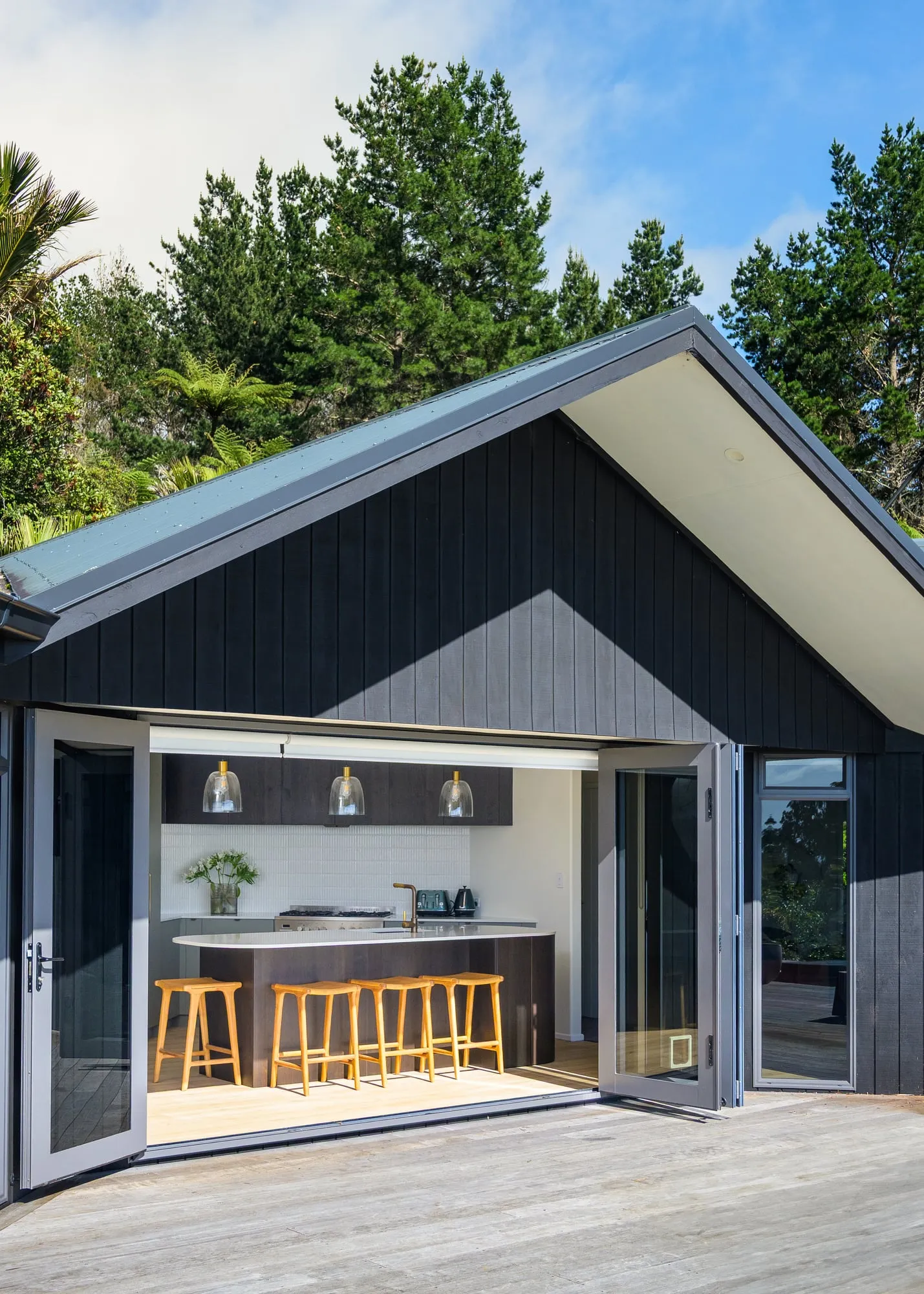 Black-clad gable exterior with bifold doors folded back to the kitchen