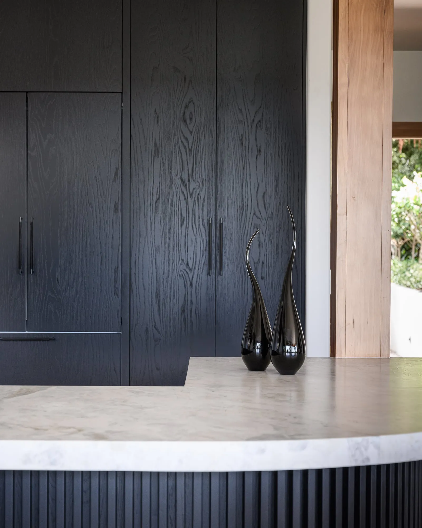 Black Oak cathedral grain, slim black bar pulls and fluted island base