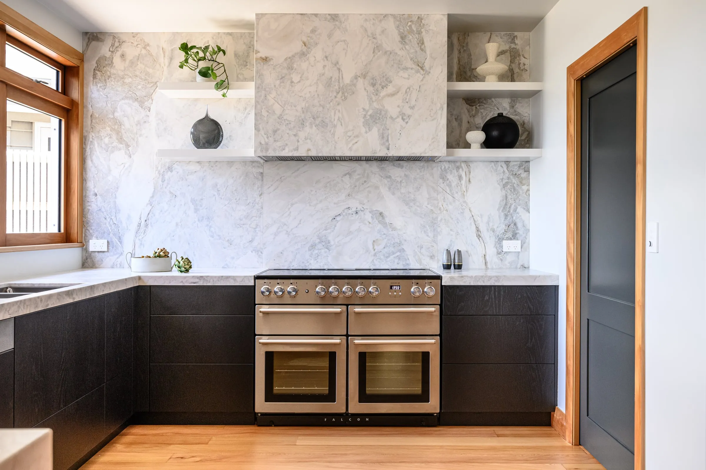 Bookmatched Quartzite splashback above the range with black Oak cabinetry