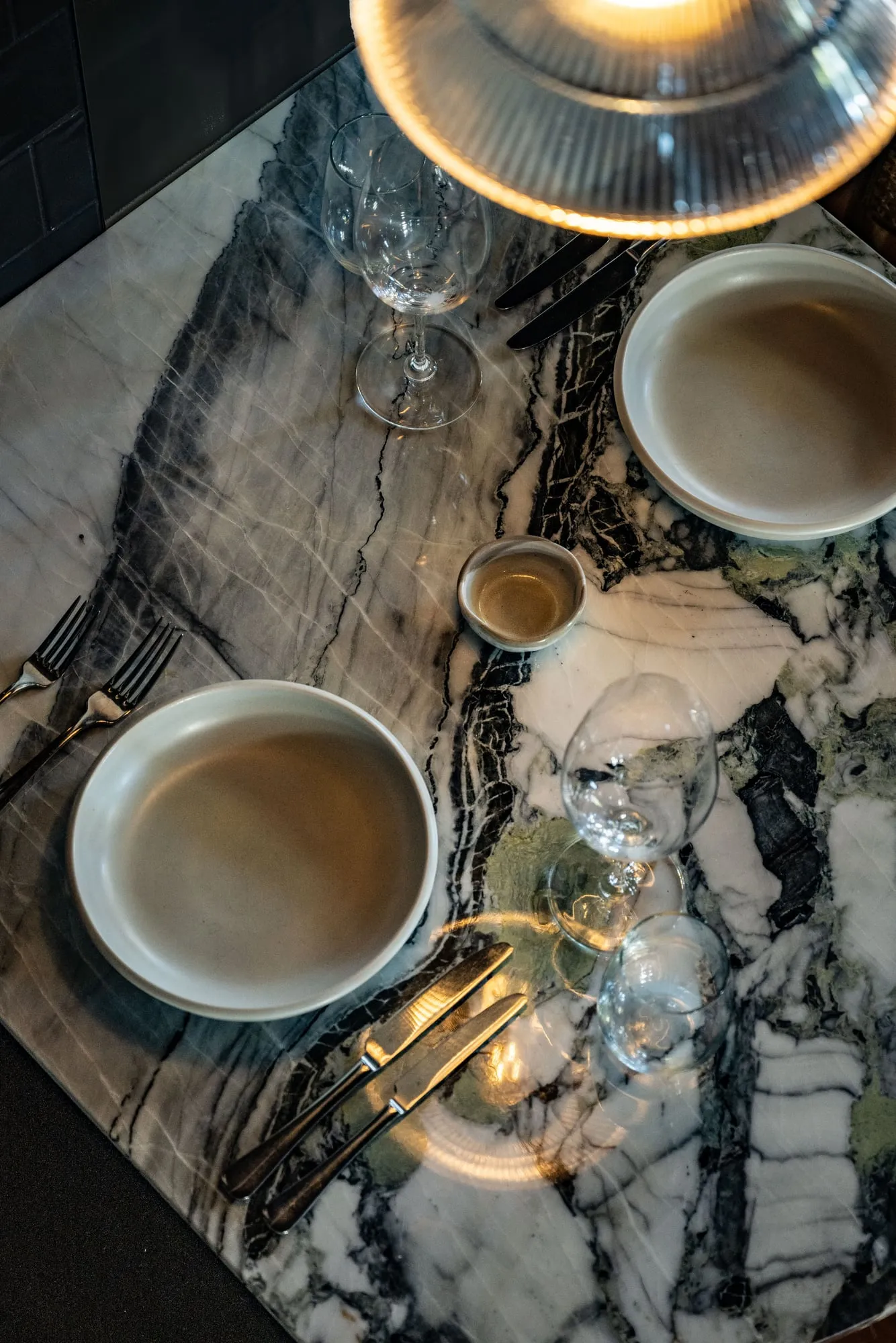 Grey-green veined Marble tabletop beneath a ribbed-glass pendant