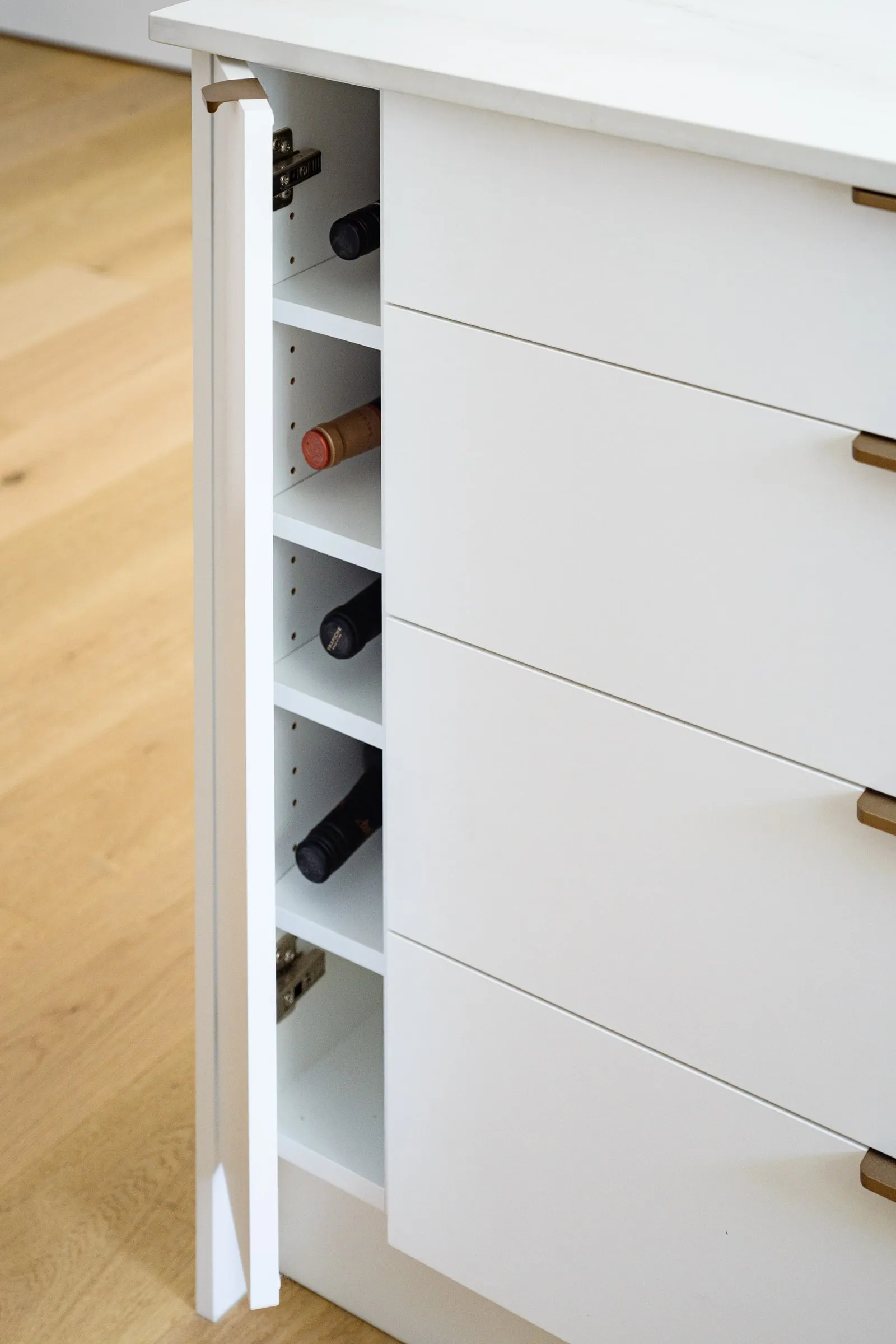Concealed wine store in an island end panel with brass edge pulls