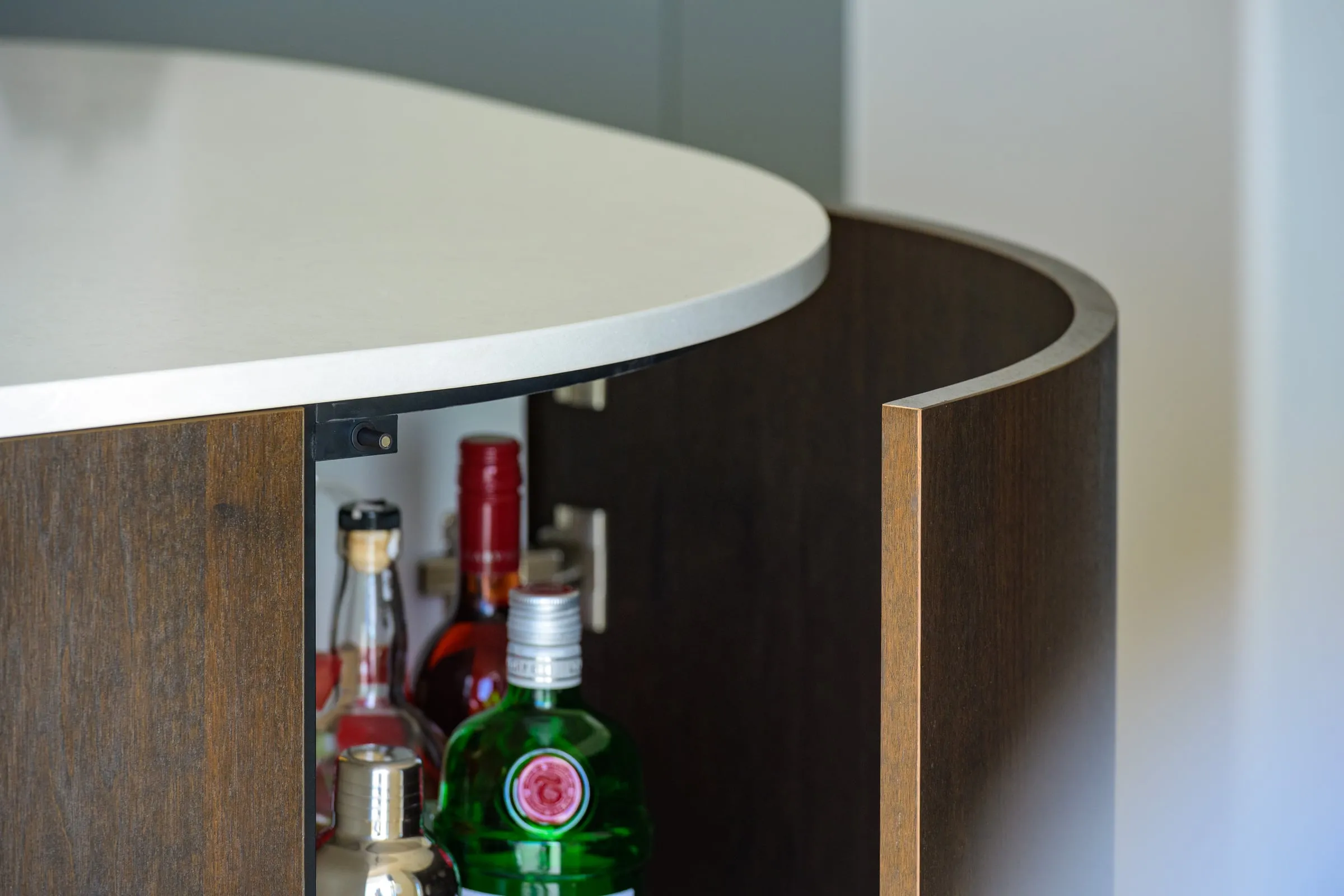 Curved veneer bar door meeting the white stone benchtop edge