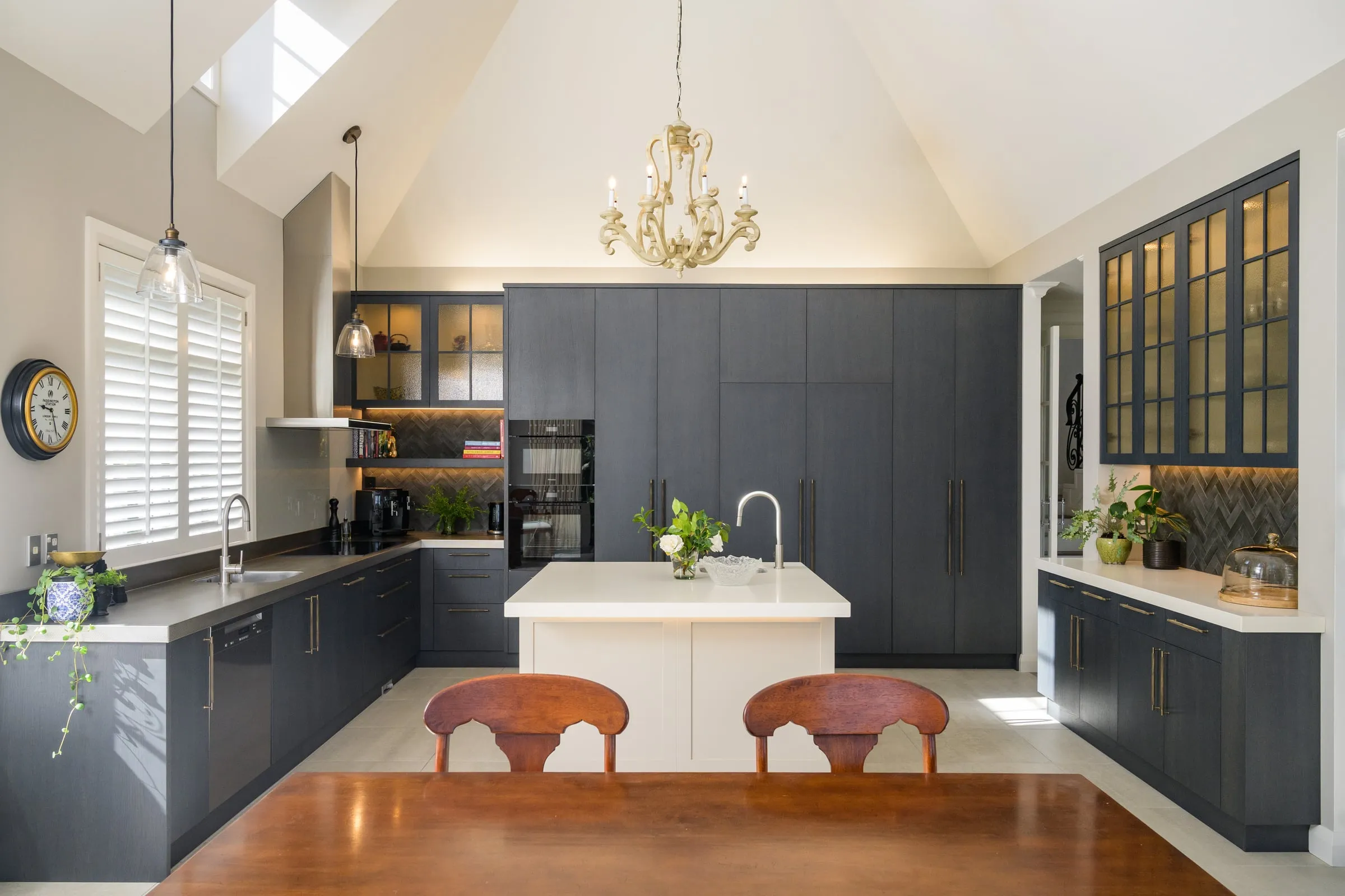 Dark Oak kitchen and island beneath a vaulted ceiling and chandelier