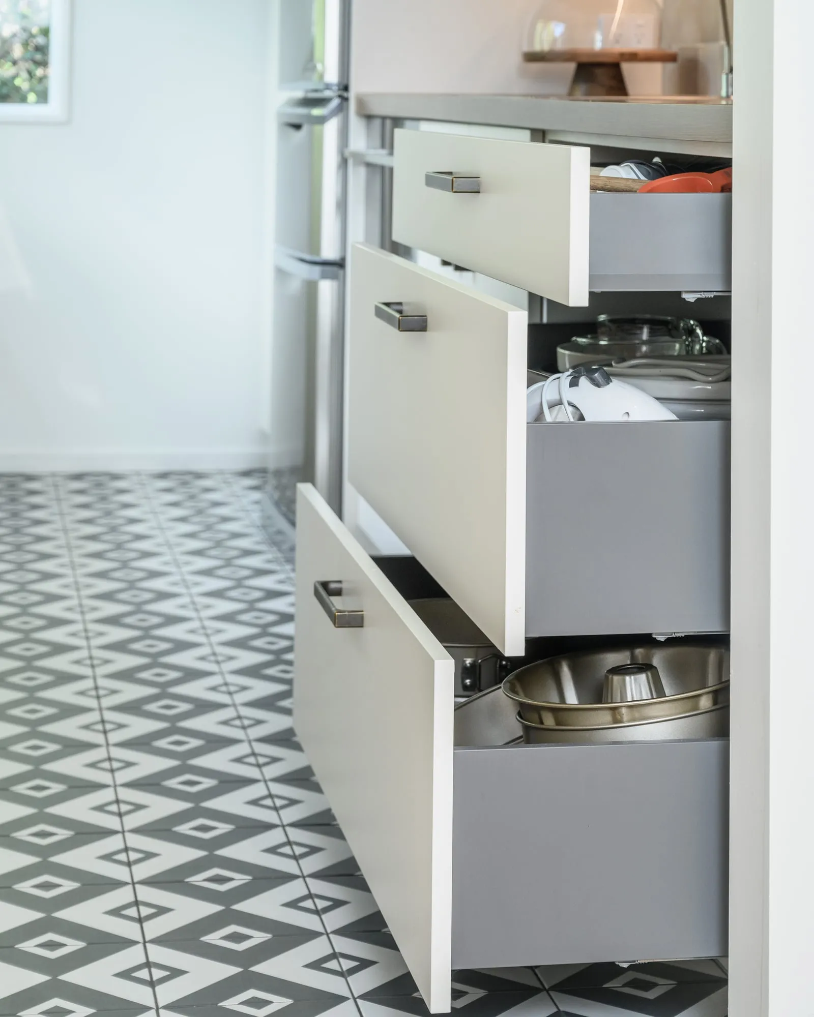 Deep pan drawers pulled open above a geometric black and white tile floor