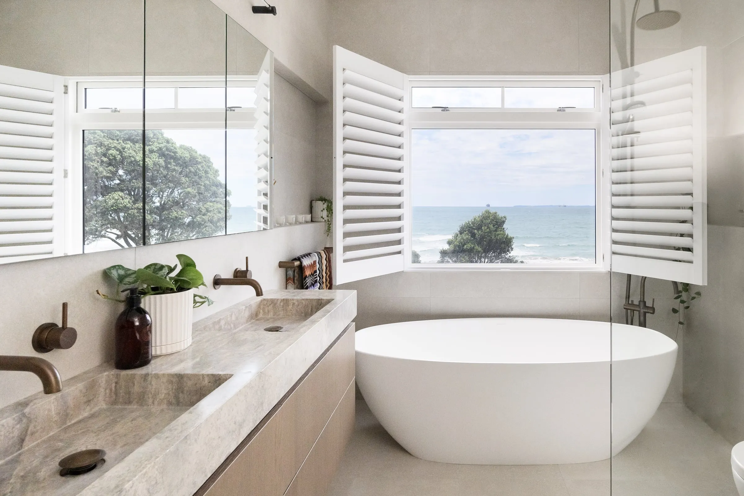 Freestanding bath with the Pacific framed in a shuttered window