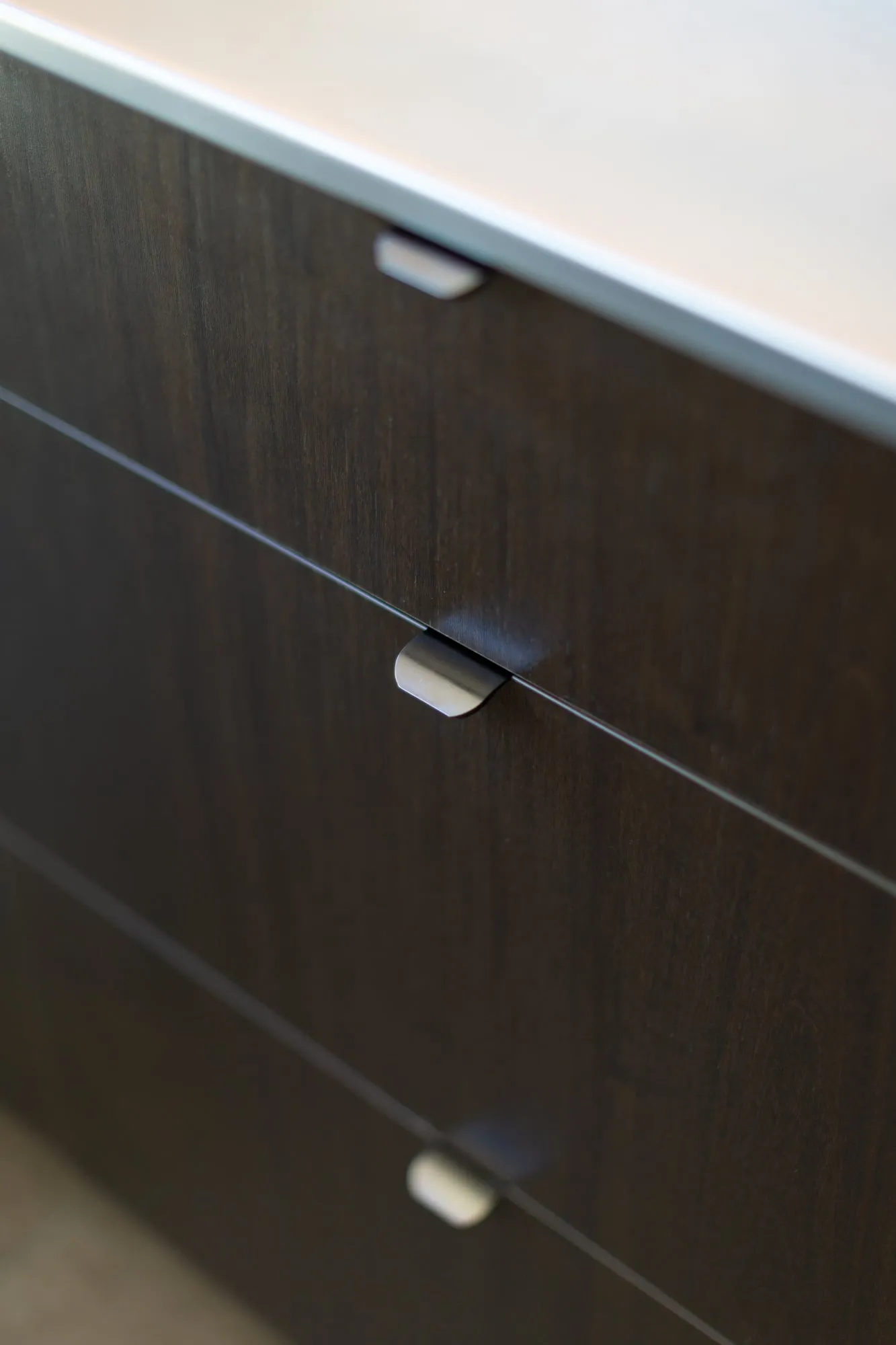 Folded-metal tab pulls set into shark-nose drawer reveals