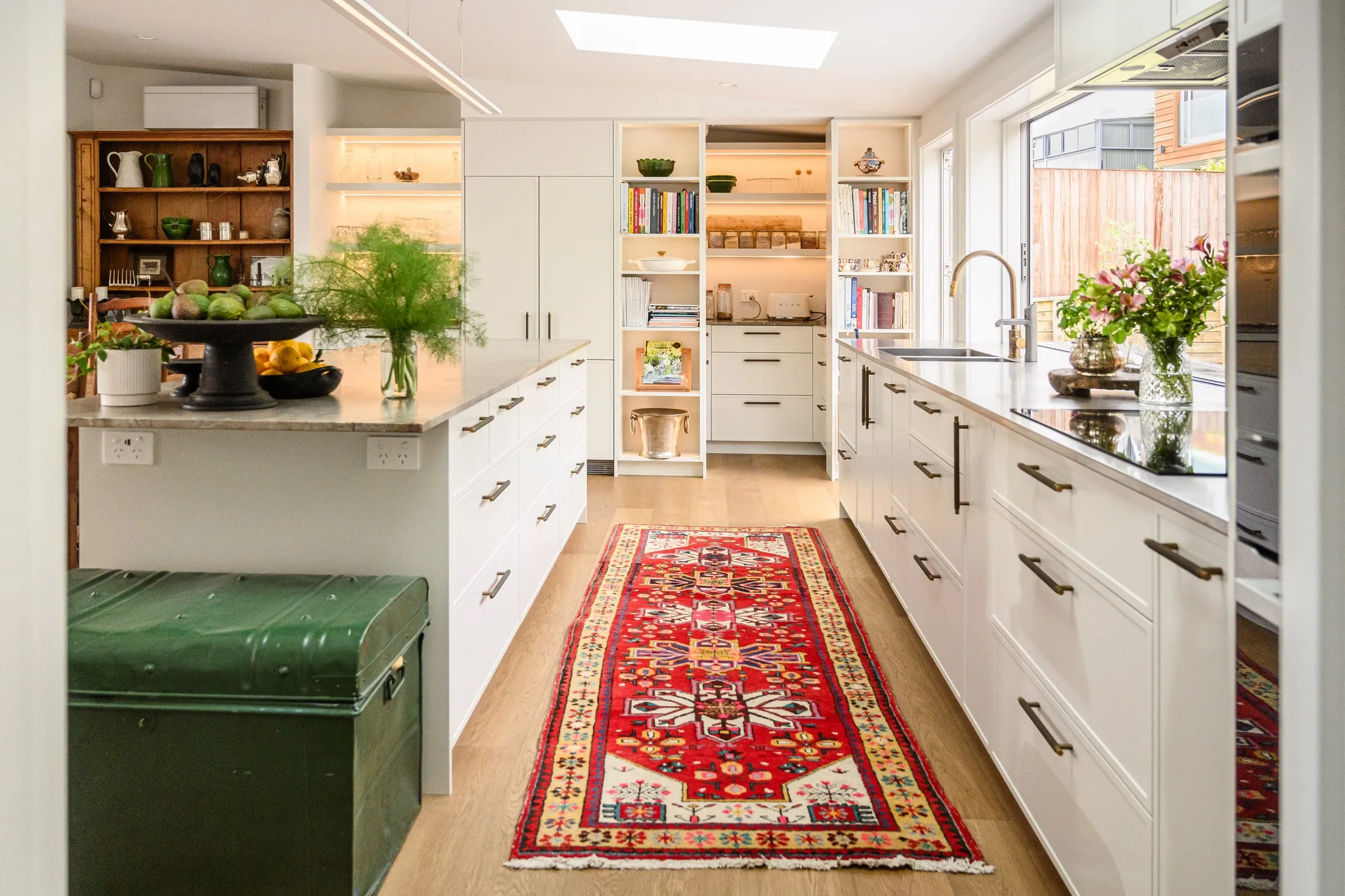 Galley kitchen with red Persian runner leading to the lit pantry