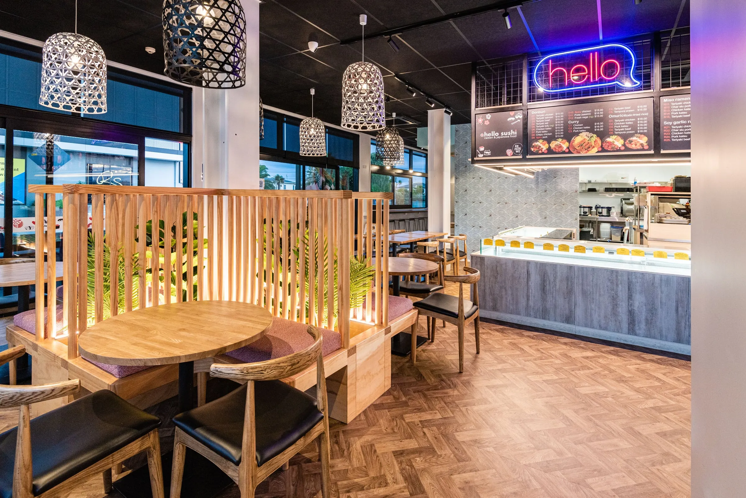 Backlit pine dowel booth screens leading toward the neon hello sign and open kitchen
