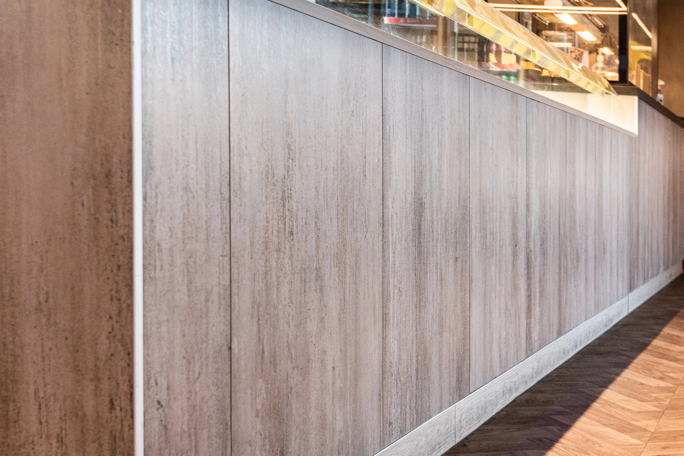 Raking view along the grey-washed counter front showing panel rhythm and shadow gaps