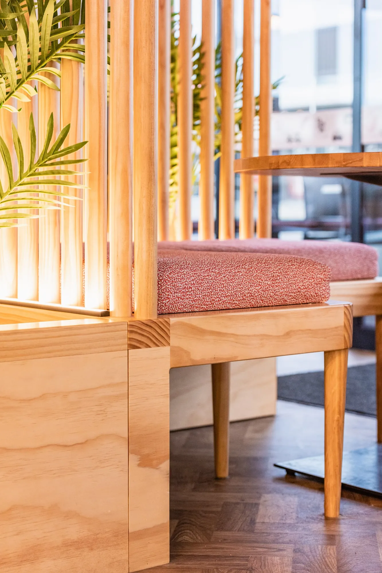 Mitred solid-pine plinth corner with rose bouclé squab and backlit dowel screen