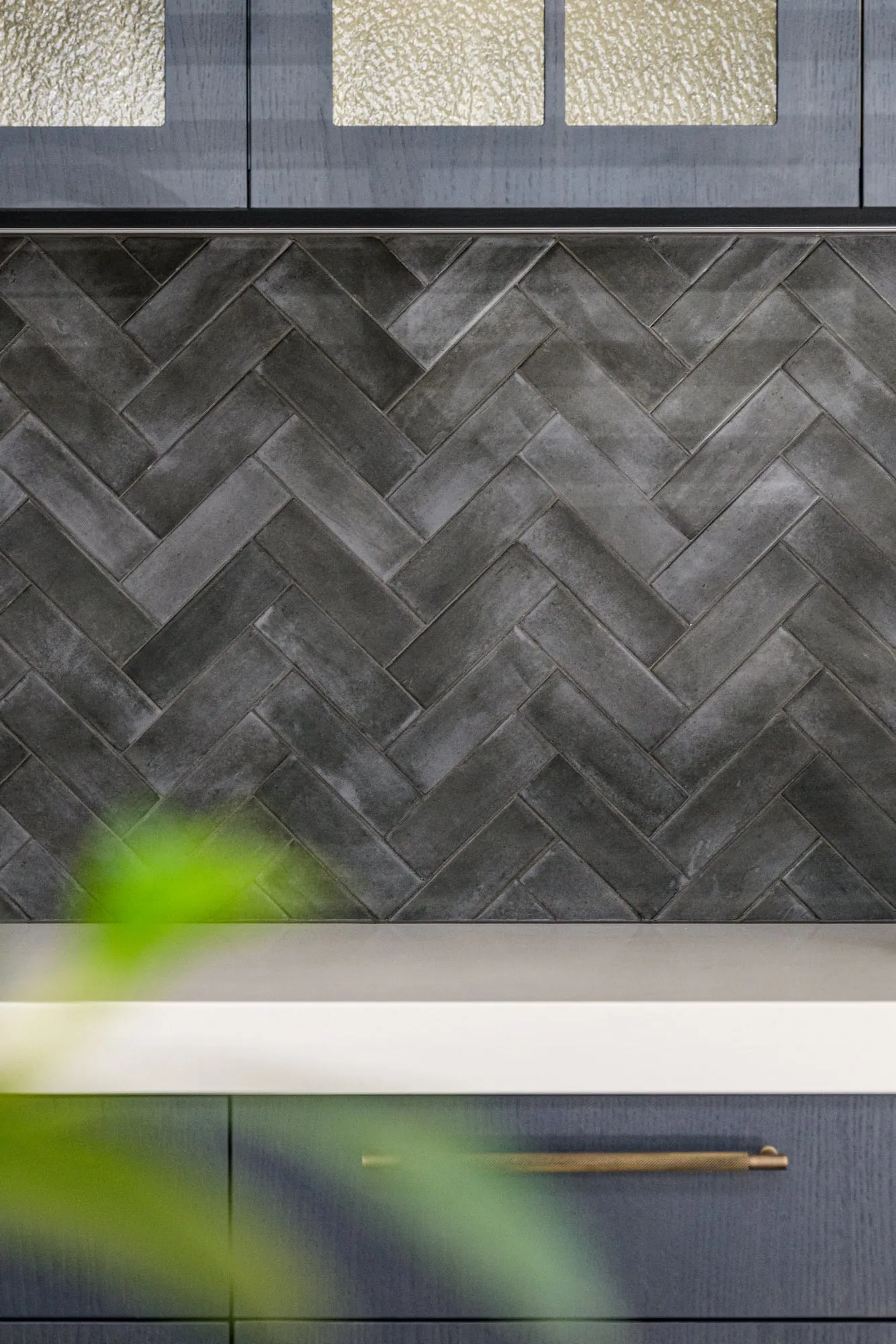 Herringbone tile meeting white quartz benchtop above a knurled brass pull