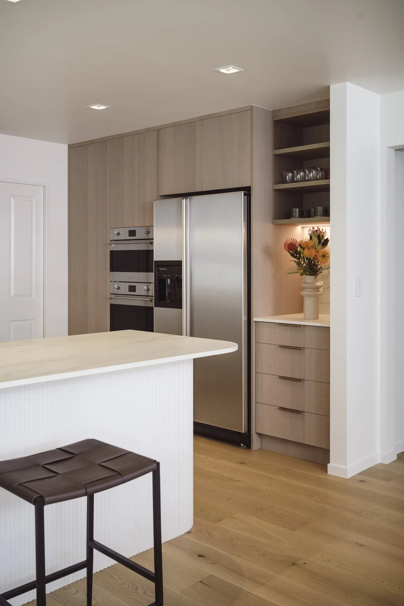 Limed Oak tall cabinetry with integrated ovens and lit shelf nook