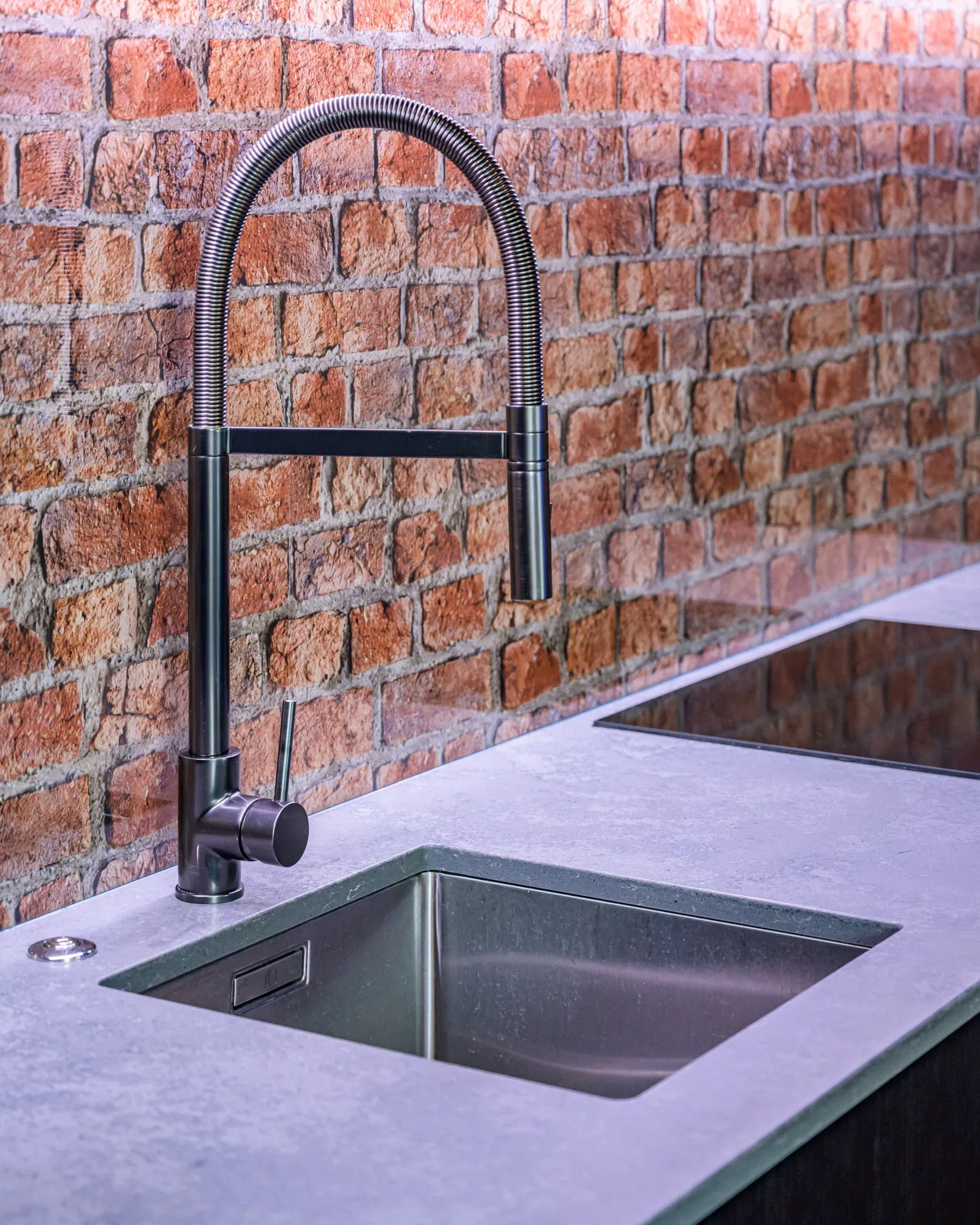 Coiled matte black tap and undermount sink against recycled brick