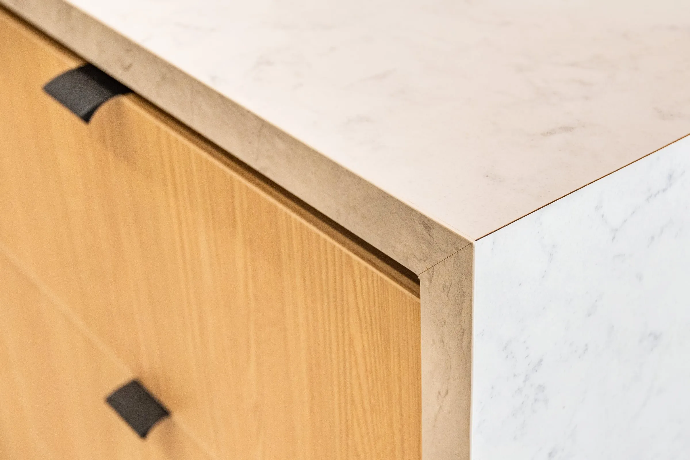 Mitred quartz waterfall corner over Oak drawers with black tab pulls