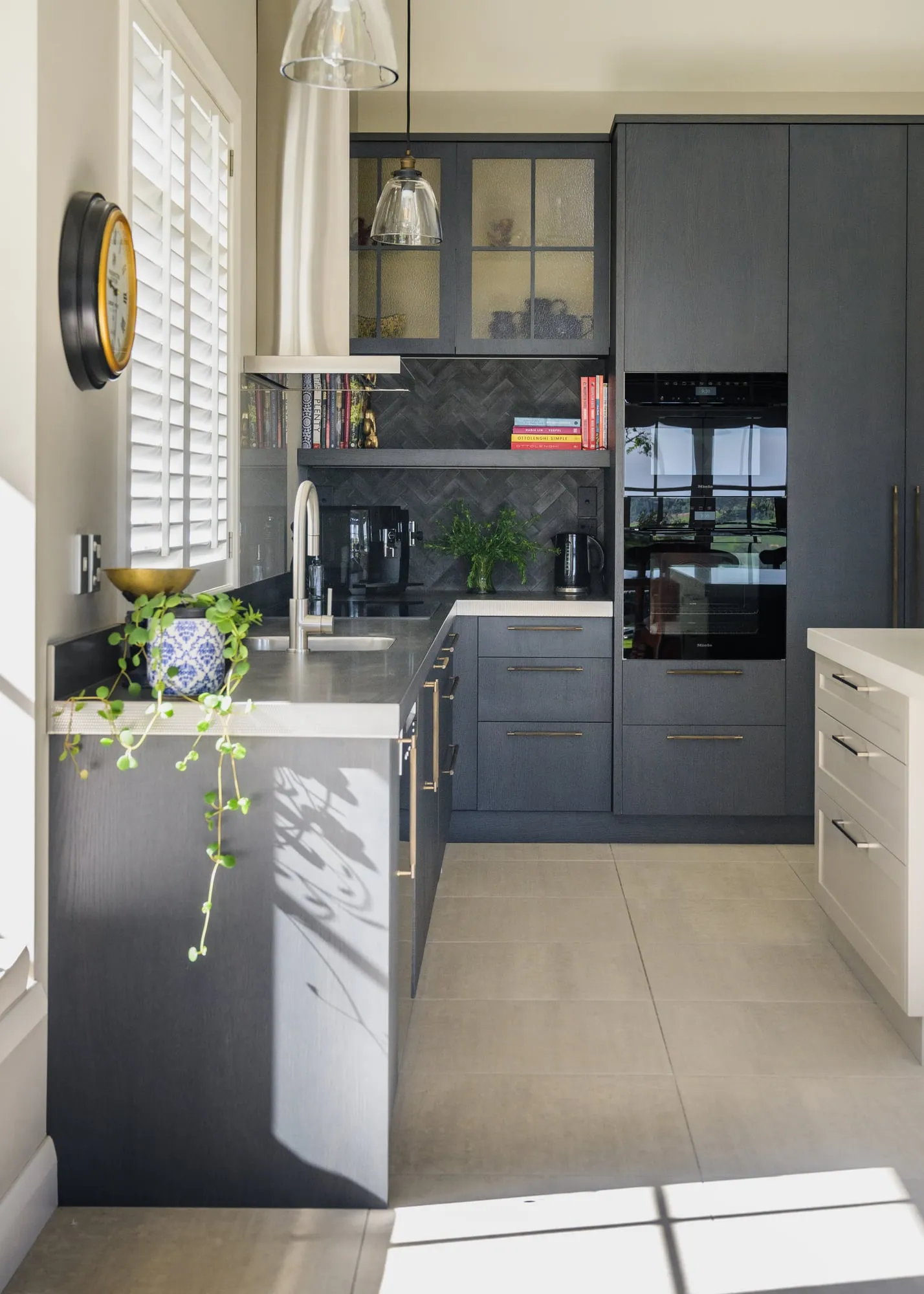 Morning sun casting dappled plant shadows across dark Oak cabinetry