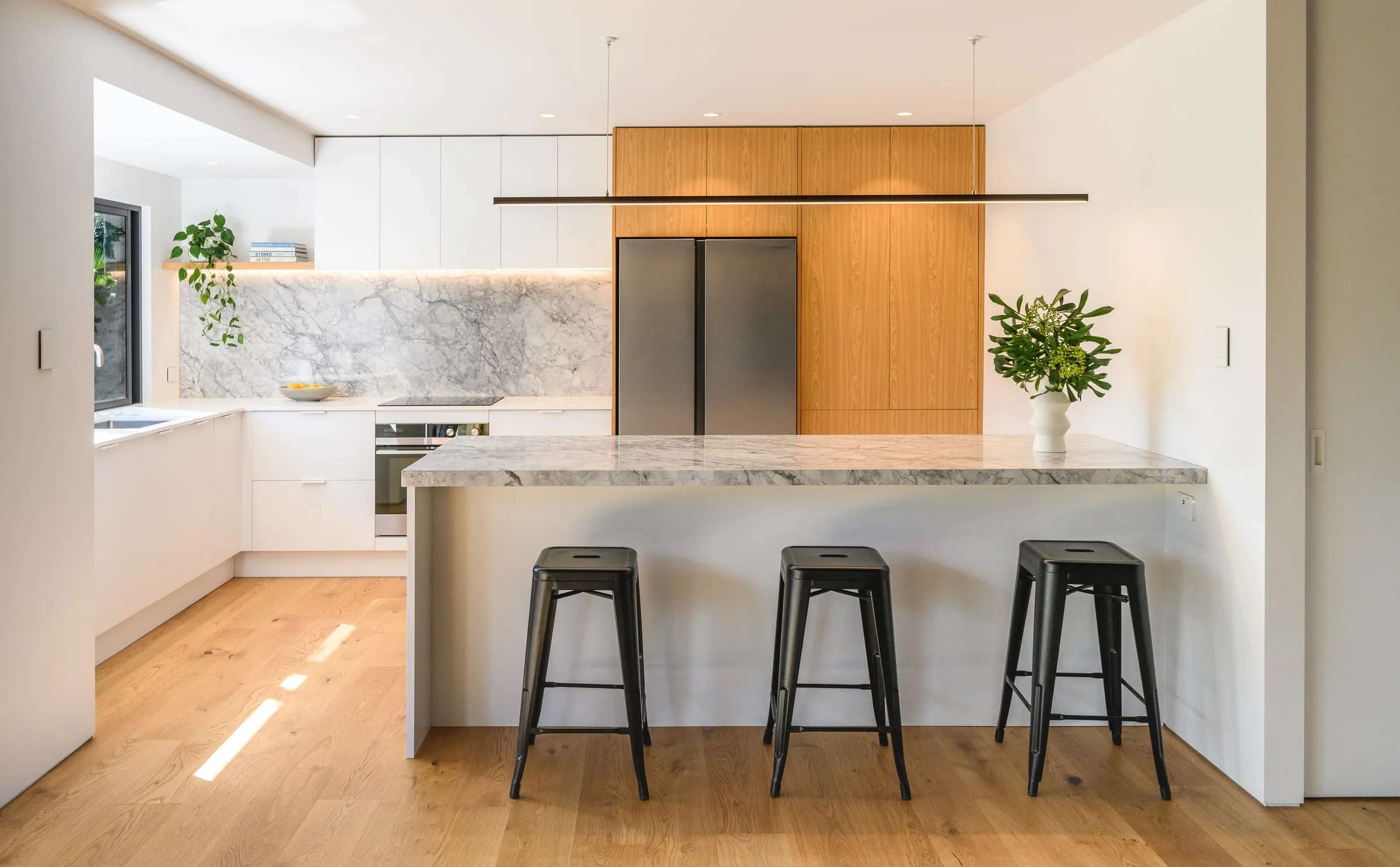 Matte white and Oak kitchen with grey-veined stone island and splashback, Kotuku Place, Matua