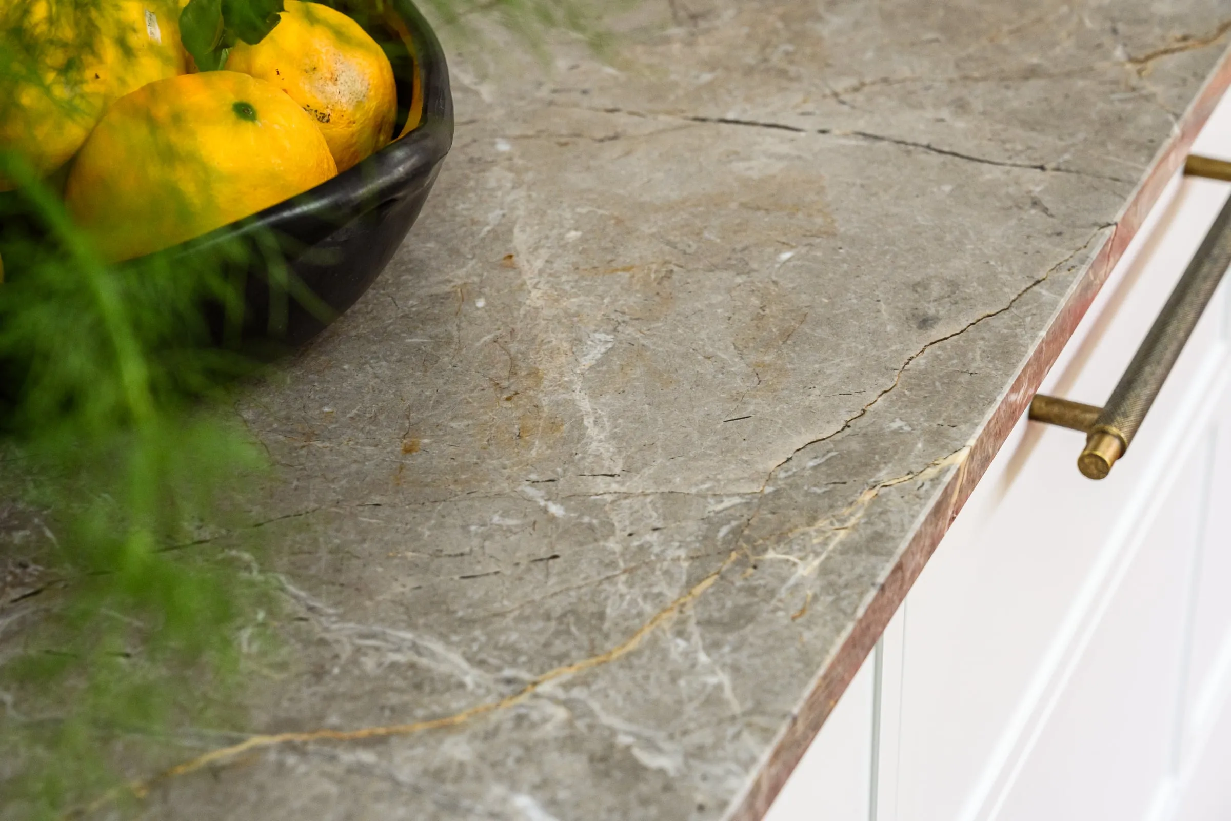 Ochre-veined stone benchtop edge with knurled aged-brass pull