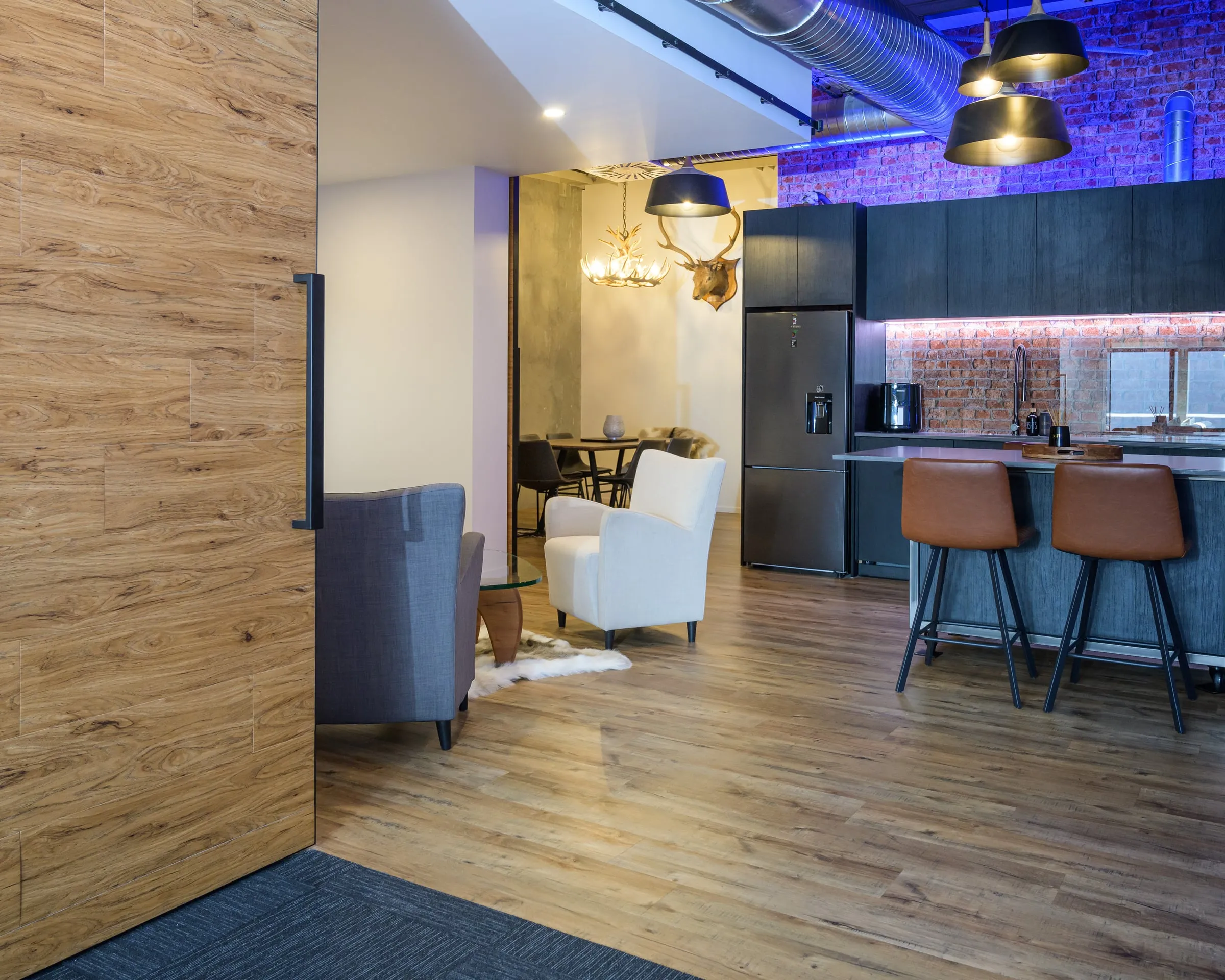 Open-plan view linking lounge, dining and the dark kitchen