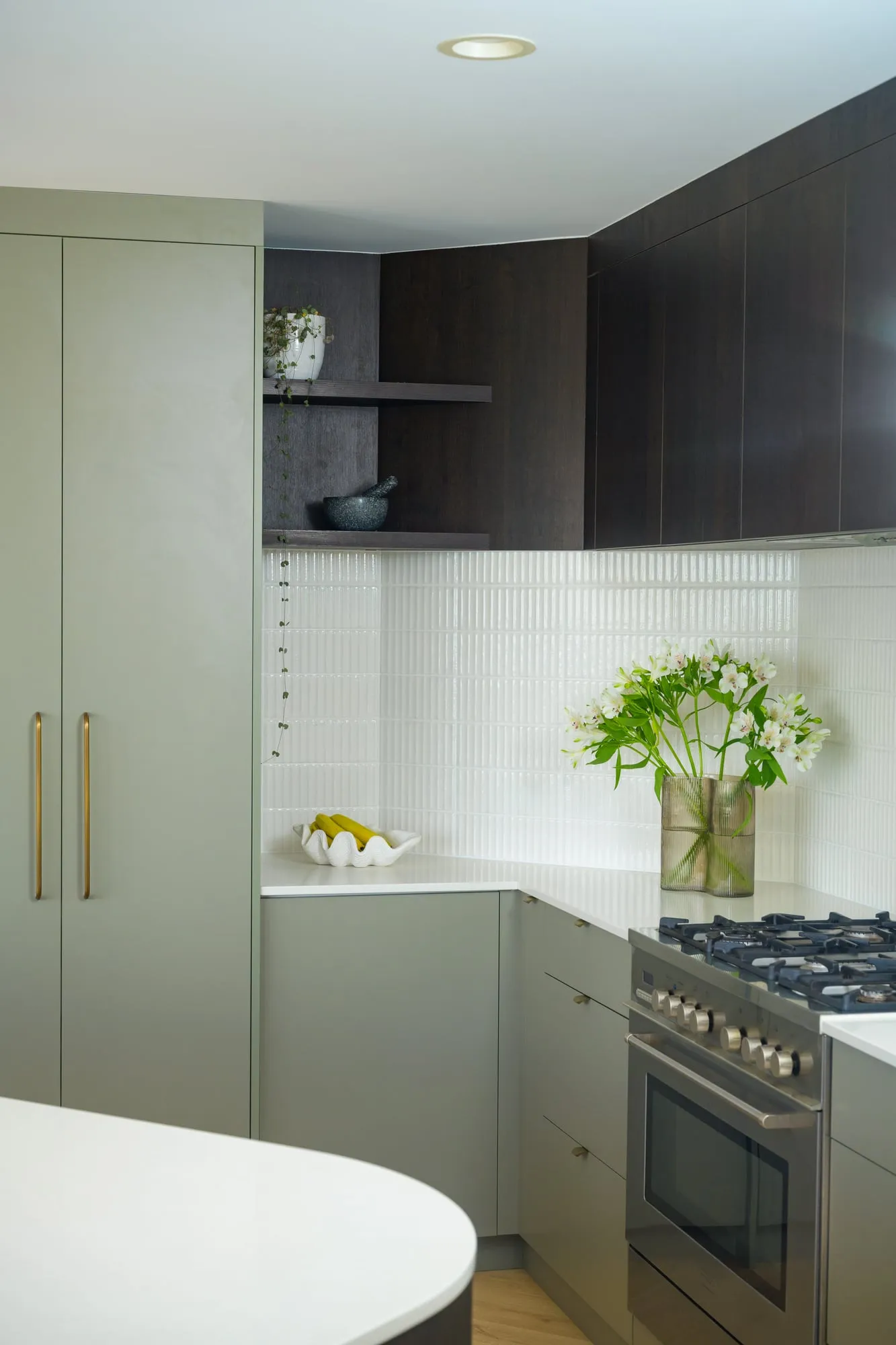 Open dark-timber shelves with trailing plant beside a white tile splashback
