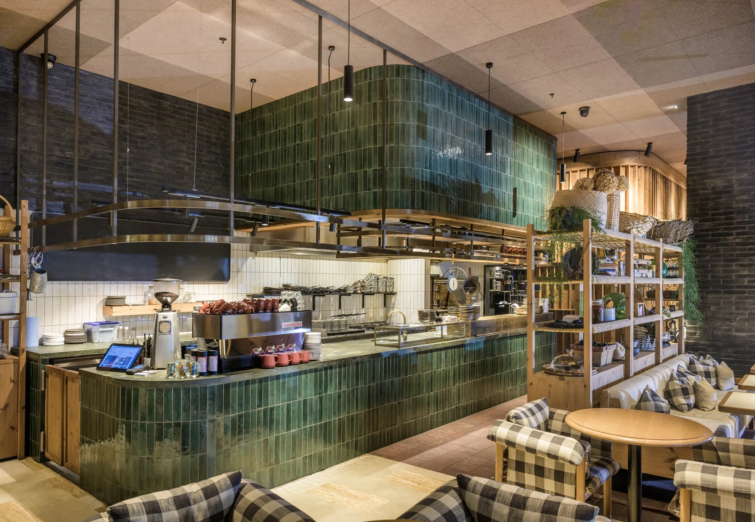 Curved green-tiled bar with brass shelf rails and timber display shelving