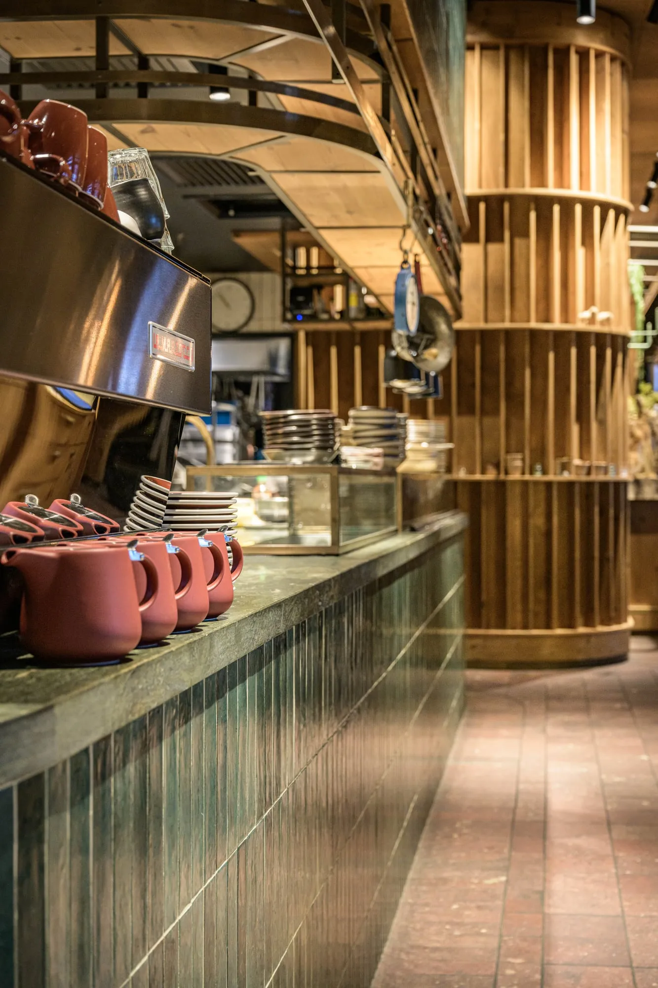 Green stone benchtop edge over vertical glazed tile with terracotta teapots