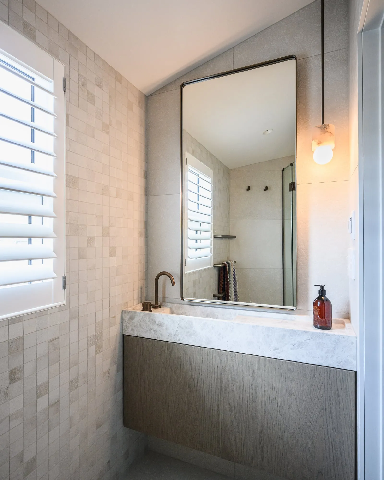 Timber veneer vanity with carved stone trough basin and brass tap