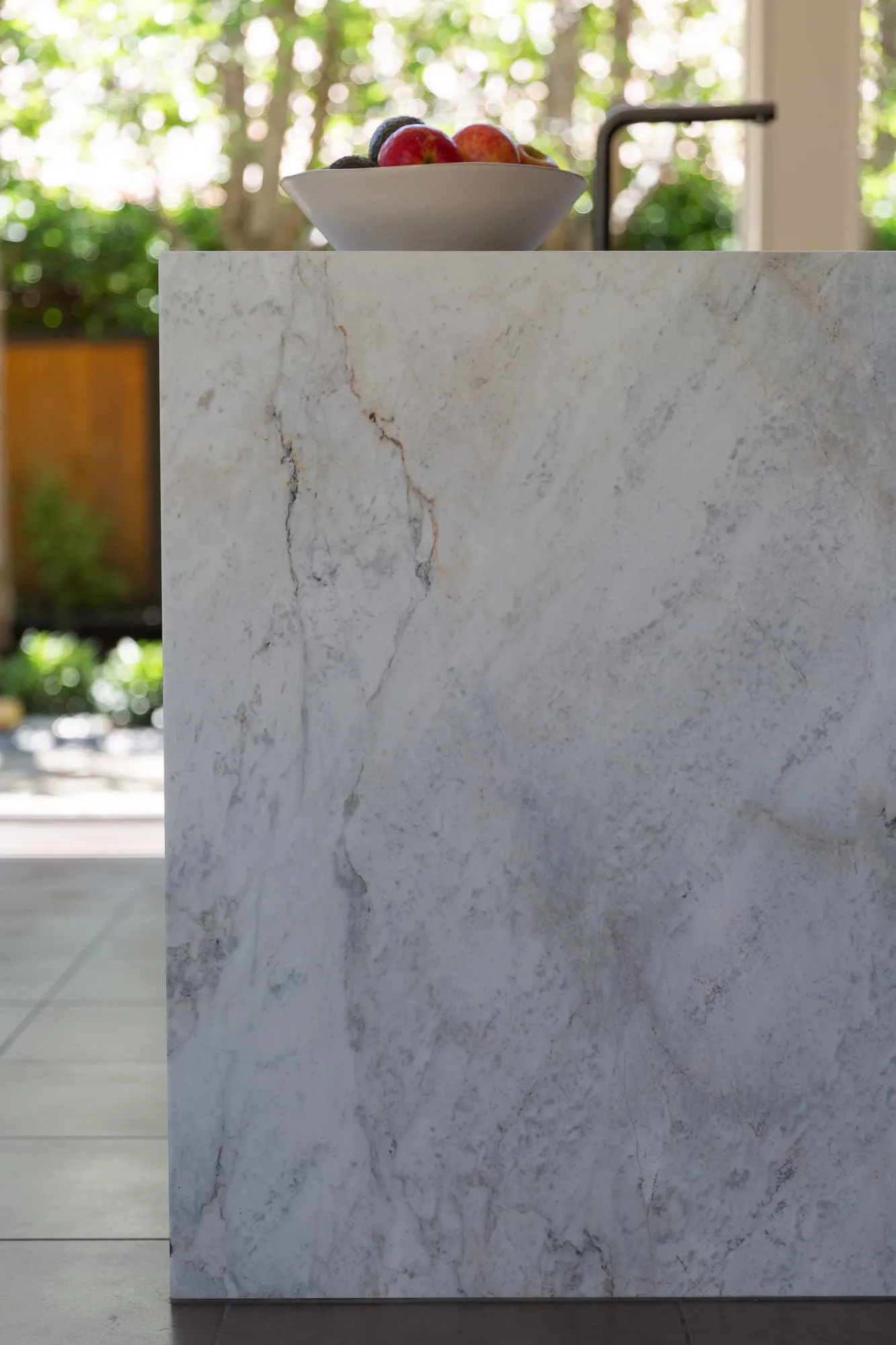 Veined Quartzite waterfall edge on the island with garden light behind