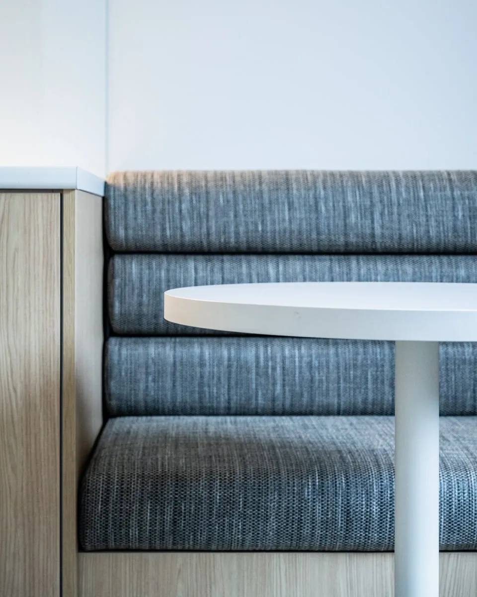Rolled banquette upholstery meeting the blond Oak plinth edge
