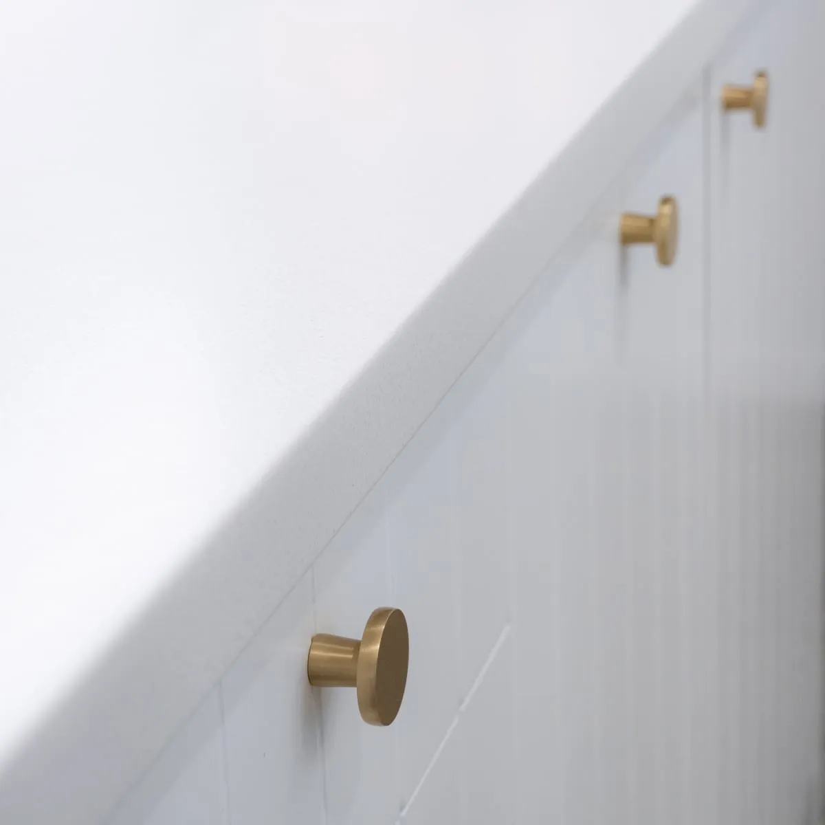 Brass disc knobs receding in soft focus along the island edge