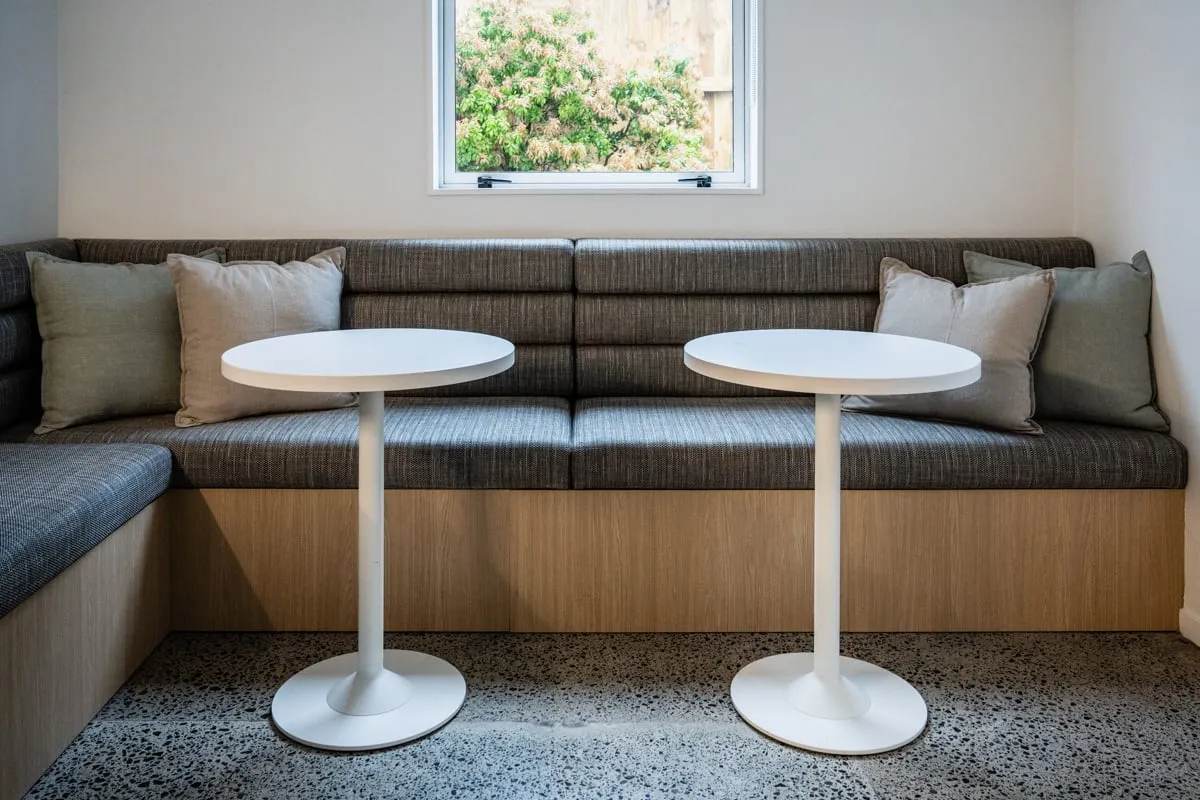 Corner banquette on a blond Oak plinth with white pedestal tables