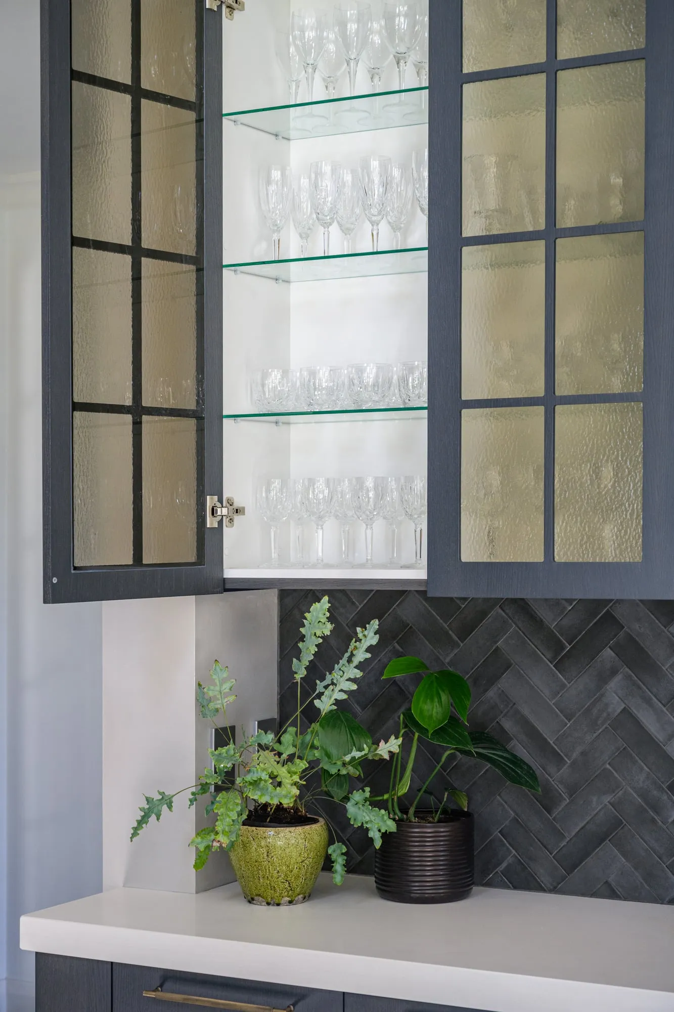 Open display door showing crystal glassware on glass shelves