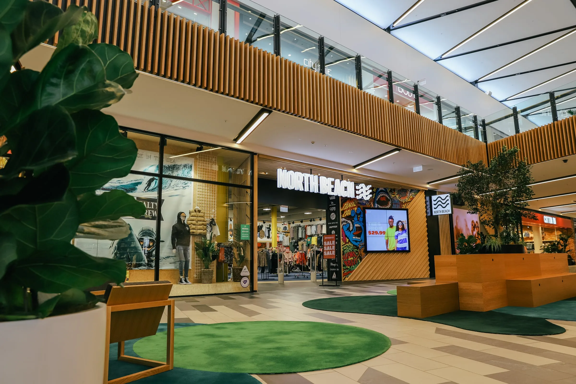 Shopfront elevation with fiddle-leaf foreground and forest-green rugs