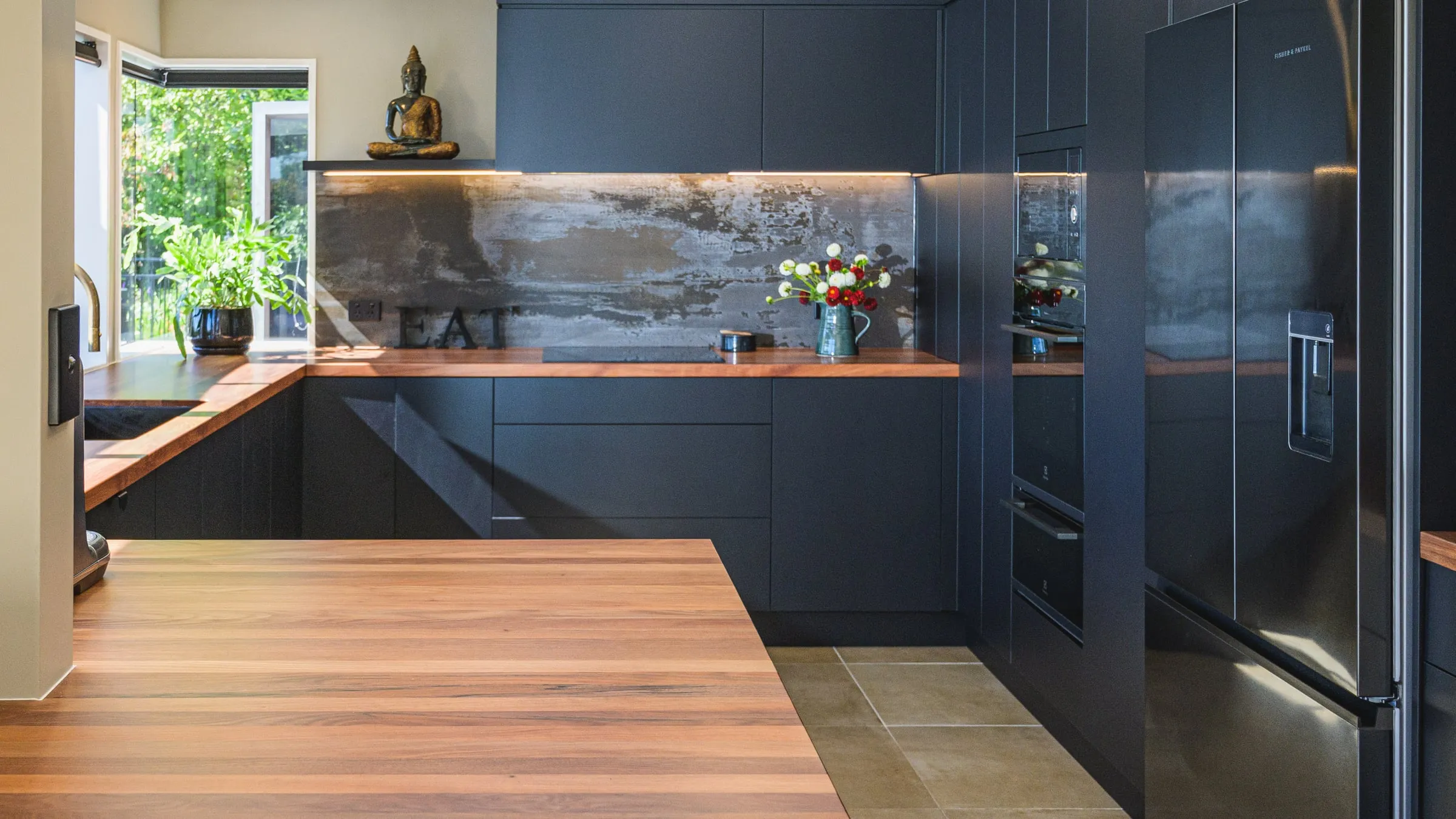 Panorama across the timber island toward the oxidised-steel splashback