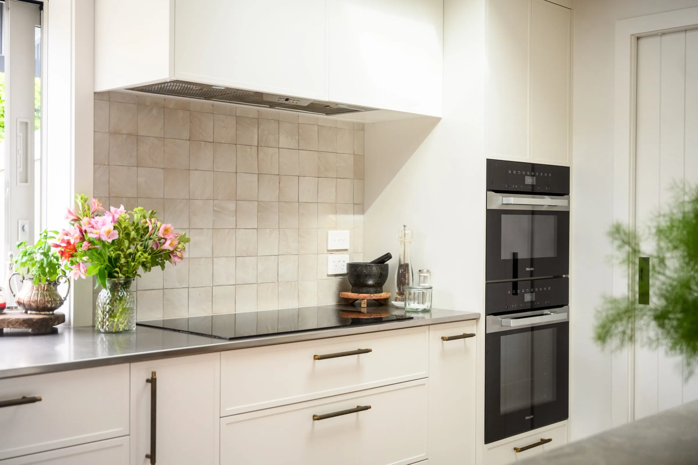 Cooktop wall with pearl-cream zellige splashback and integrated rangehood